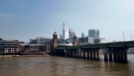 Observing-the-River-Thames,-the-Cannon-Street-Railway-Bridge,-and-the-city-skyline-in-London,-England,-embodying-a-captivating-fusion-of-urban-infrastructure-and-natural-beauty