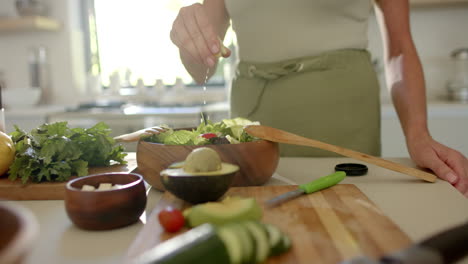 Caucasian-woman-preparing-salad-in-kitchen,-holding-wooden-spoon