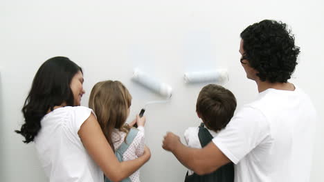 Family-painting-a-wall-at-home-with-brushes-