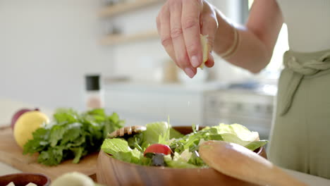 A-person-adding-seasoning-to-salad-in-a-bright-kitchen