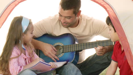 Two-kids-with-their-dad-playing-the-guitar