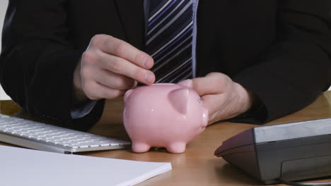 Businessman-putting-money-in-his-piggy-bank