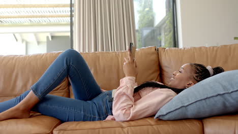 Afroamerikanische-Junge-Frau-Liegt-Auf-Der-Couch-Und-Hält-Smartphone