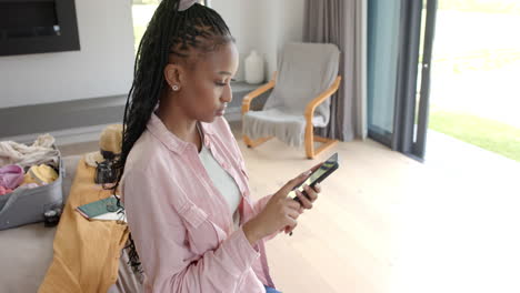 African-American-young-woman-holding-smartphone,-sitting-indoors