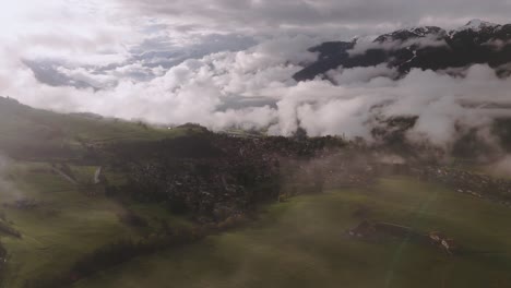 Paisaje-De-Montaña-Brumoso-Con-Nubes-Bajas-Flotando-Sobre-Campos-Verdes-Durante-El-Amanecer,-Vista-Aérea