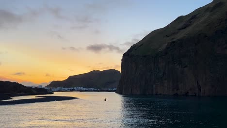 Sonnenuntergang-über-Dem-Hafen-Von-Vestmannaeyjar-Mit-Ruhigem-Wasser-Und-Dramatischen-Klippen