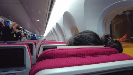 Panning-shot-of-Chinese-people-inside-aircraft-placing-hand-luggage-in-cabin-Beijing-Capital-airport-during-Covid-19-pandemic