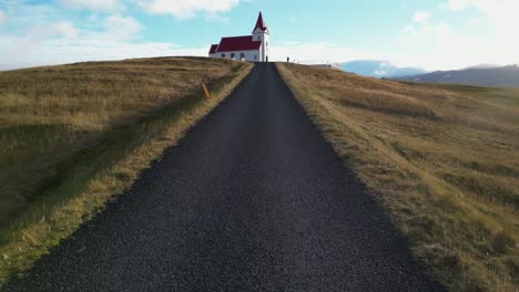 Drone-shot-of-road-leading-to-church-in-Iceland-during-winter