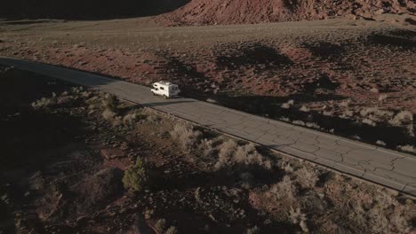 Aerial-view-of-a-van-gracefully-traversing-the-road-through-Indian-Creek,-a-renowned-rock-climbing-destination-in-Utah,-USA,-blending-adventure-and-freedom-on-the-open-road