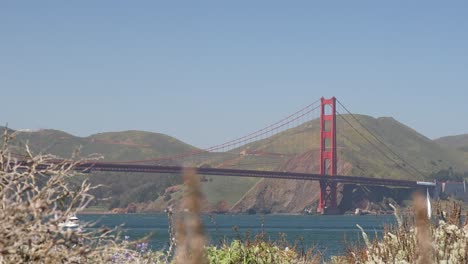 Golden-Gate-Bridge-In-San-Francisco-Mit-Vorbeifahrendem-Weißen-Boot,-Aufnahme-Aus-Niedriger-Perspektive-Von-Crissy-Field-South-Beach,-Kalifornien,-USA