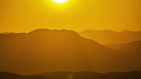 Zeitraffer-Sonnenuntergang-Goldene-Gelbe-Skyline-über-Berggipfeln-Enthüllt-Sonnenball-Fallen