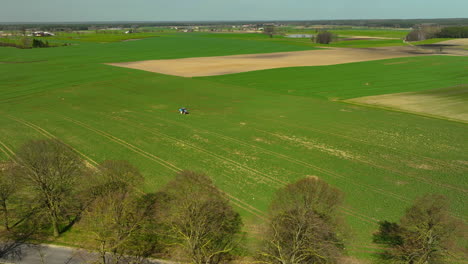 Luftaufnahme-Von-Ausgedehnten-Grünen-Feldern-Mit-Einem-Einzigen-Traktor-Sichtbar