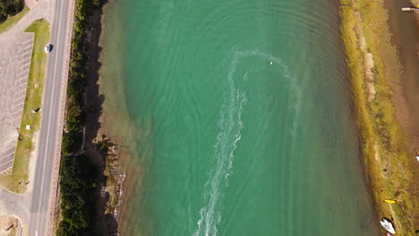 Drone-tilt-up-over-Goukou-estuarine-river-with-leisure-crafts-speeding-around
