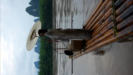 Hanfu-Mädchen-Richtet-Ihr-Haar-Und-Hält-Einen-Sonnenschirm,-Während-Sie-Auf-Einem-Bambusfloß-Am-Li-Fluss-Steht