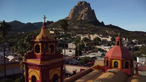 Campanario-Rojo-Y-Amarillo-De-Un-Famoso-Pueblo-De-México-Llamado-Bernal,-Con-Uno-De-Los-Tres-Monolitos-Más-Grandes-Y-Bellos-Del-Mundo-Al-Fondo,-Hermano-Del-Peñón-De-Gibraltar.