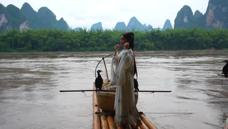 Chinesisches-Hanfu-Mädchen-Richtet-Ihr-Haar,-Während-Es-Auf-Einem-Bambusfloß-Am-Li-Fluss-Steht,-Xingping