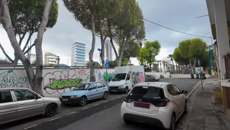 A-quiet-street-in-Nicosia,-Cyprus,-lined-with-cars-and-featuring-a-graffiti-decorated-wall
