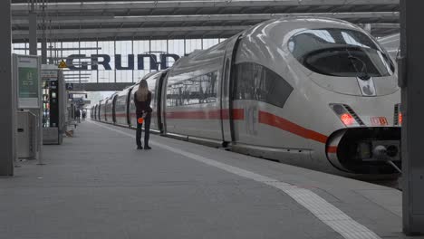 Static-shot-of-a-woman-at-Munich-central-station-next-to-a-Deutsche-Bahn-train