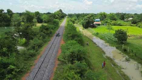 Rolling-Through-Rural-Farmland-On-The-Bamboo-Railway-Near-Battambang-Cambodia-Drone-Tracking-From-Behind