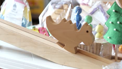 Small-wooden-dinosaur-slowly-moves-down-ramp,-handmade-toy