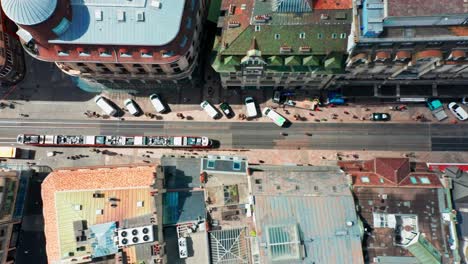 Top-down-aerial-of-a-tram-driving-through-a-busy-street-in-down-town-Geneva,-Switzerland