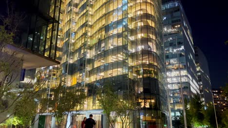 Toma-En-Primera-Persona-Frente-A-Un-Edificio-De-Oficinas-Iluminado,-En-Nueva-Las-Condes,-Chile.