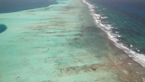 Kitesurfer-Gleiten-über-Das-Klare-Blaue-Wasser-Des-Los-Roques-Barrier-Reef,-Luftaufnahme