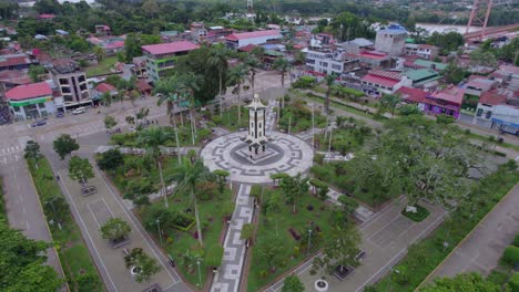 Experience-the-beauty-of-Puerto-Maldonado's-Main-Square-with-palm-trees-and-an-iconic-monument-in-this-stunning-drone-flight