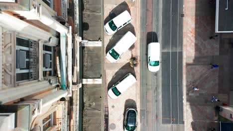 Top-down-aerial-reveal-of-a-busy-street-with-walking-pedestrians-in-downtown-Geneva,-Switzerland-on-a-sunny-day