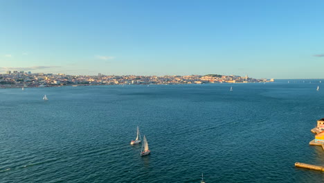 Vista-Aérea-Del-Río-Tajo-Y-La-Ciudad-De-Lisboa-Con-Veleros-Navegando-En-Un-Día-Soleado-De-Verano