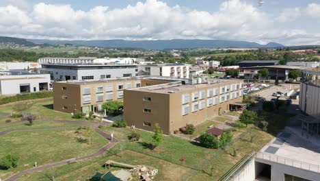 Aerial-of-a-large-retirement-home-with-a-large-green-garden-with-a-beautiful-Swiss-landscape-in-the-background