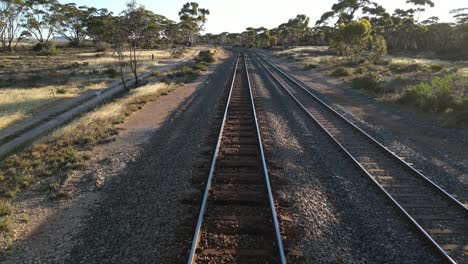POV-shot-over-train-rail-tracks-in-tropical-landscape-of-Australia-during-sunset-time
