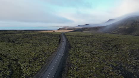 Toma-De-Drone-De-Un-Automóvil-Conduciendo-En-Islandia-Durante-El-Invierno-En-Un-Campo-De-Musgo