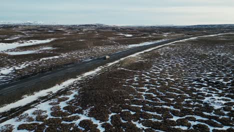 Toma-De-Drone-De-Un-Automóvil-En-Una-Carretera-En-Islandia-Durante-El-Invierno-Con-Nieve