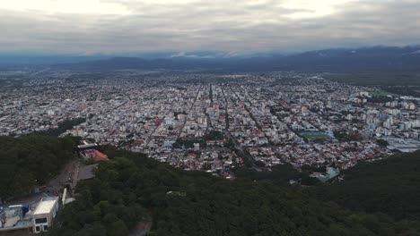 Luftbild-Drohne-Mit-Umlaufbahn-Mit-Blick-Auf-Das-Haus-Auf-Dem-Berggipfel-Und-Salta,-Die-Hauptstadt-Der-Argentinischen-Provinz-Salta