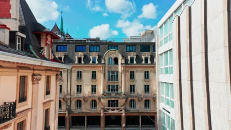 Drone-flying-between-historical-and-modern-buildings-in-downtown-Geneva,-Switzerland-towards-the-facade-of-monumental-structure