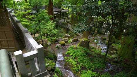 Beautiful-Japanese-temple-inside-lush-green-forest-with-small-river