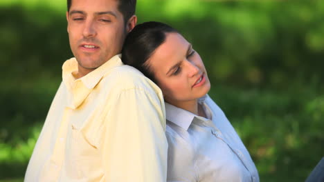 Lovers-sitting-back-to-back-on-the-grass-