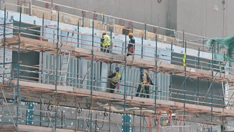 Trabajadores-Que-Trabajan-En-Una-Plataforma-Suspendida-En-Un-Sitio-De-Construcción-Durante-Un-Caluroso-Día-De-Verano-En-Dubai,-Emiratos-Árabes-Unidos