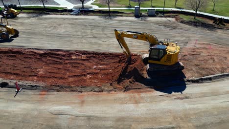 Aerial-Drone-Tracking-Track-hoe-As-The-Operator-Plays-With-Dirt-While-Waiting-For-Dump-Truck-To-Arrive