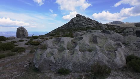 lateral-flight-in-an-area-of-sacred-rocks-in-the-background-there-is-a-monumental-one-with-its-explanatory-sign-and-in-the-foreground-we-see-one-with-many-bowls-used-for-rituals-and-offerings