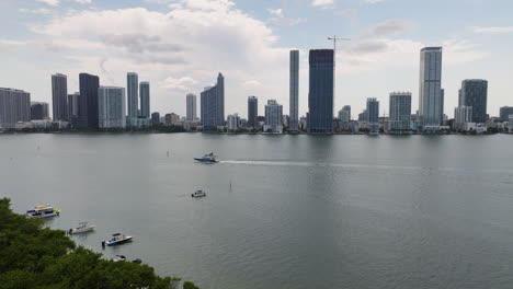Aerial-view-toward-a-yacht-driving-in-front-of-high-rise-of-Miami,-Florida,-USA