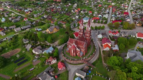 A-historic-red-brick-church-surrounded-by-a-small-village-in-lithuania,-aerial-view