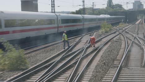 Cockpit-view-of-a-train-approaching-a-busy-rail-yard-with-workers-on-tracks