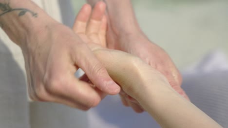 Eine-Tätowierte-Hand-Gibt-An-Einem-Sonnigen-Tag-Am-Strand-Eine-Entspannende-Massage,-Nahaufnahme