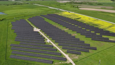 Eine-Große-Solarpanel-Farm-Auf-Einer-Grünen-Wiese-An-Einem-Sonnigen-Tag,-Luftaufnahme
