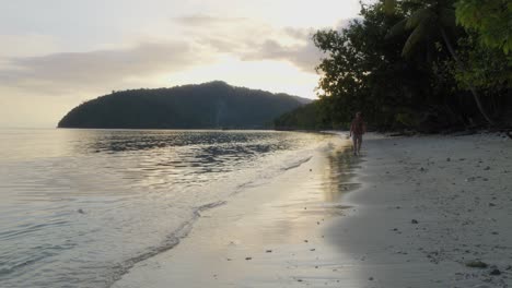 Un-Hombre-Camina-Por-La-Tranquila-Playa-De-La-Isla-Kri-En-El-Archipiélago-De-Raja-Ampat,-Indonesia