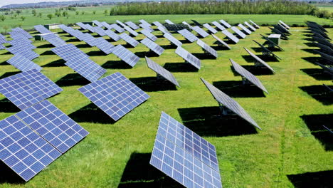 Rows-of-solar-panels-on-a-green-field-under-a-clear-sky,-aerial-view