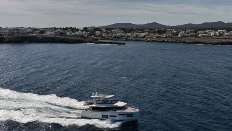 Drone-shot-of-boat-driving-next-to-Spanish-harbor-town-in-slow-motion-filmed-by-drone