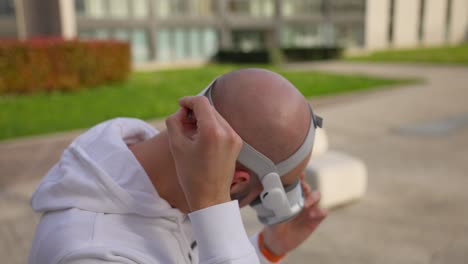 Un-Hombre-Caucásico-Ajusta-Las-Correas-Mientras-Usa-Auriculares-Vr-Blancos-Al-Aire-Libre